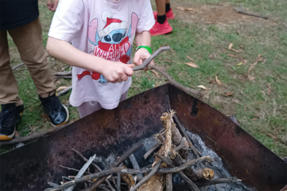 a child putting sticks into a firepit in preparation to light a fire