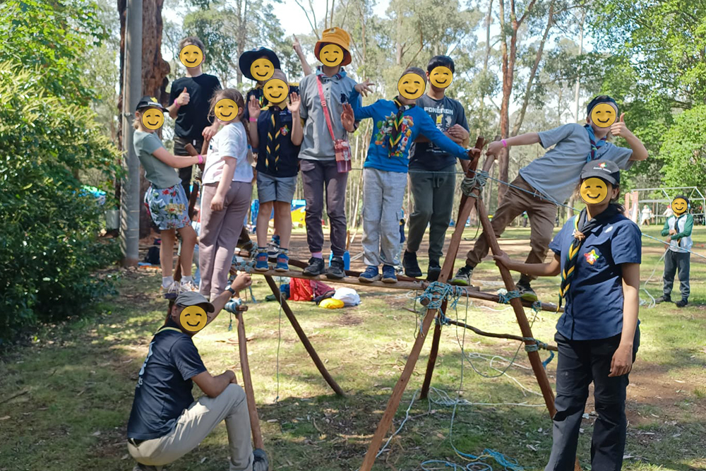 a hand-made construction out of wooden poles with children standing on top of it to test how sturdy it is.
