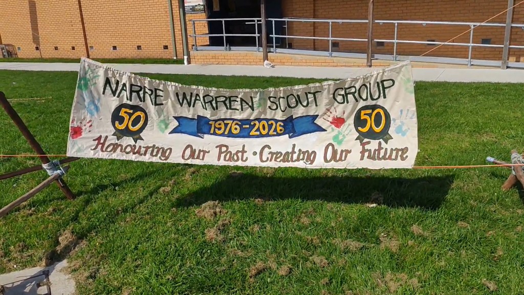 large hand-made banner outside the Scout hall that says "Narre Warren Scout Group 1976-2026: Honouring our past, creating our future
